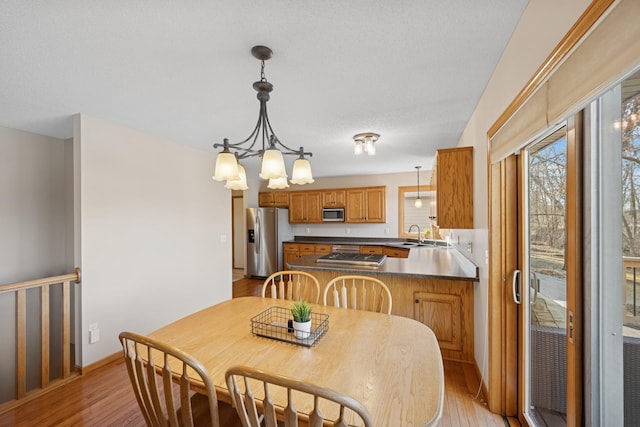 dining space featuring a notable chandelier, baseboards, and light wood-type flooring