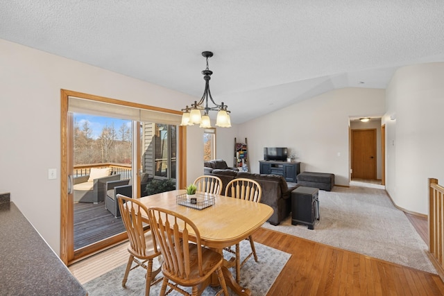 dining room with a chandelier, lofted ceiling, a textured ceiling, and light wood-style flooring