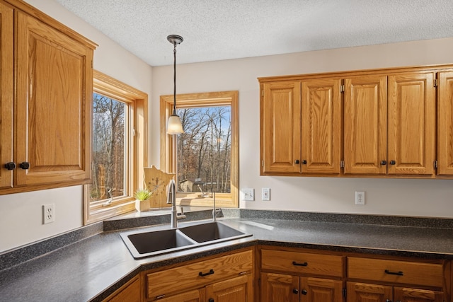 kitchen featuring a sink, dark countertops, pendant lighting, and brown cabinetry