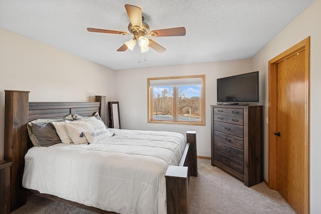 bedroom with ceiling fan, light colored carpet, and a textured ceiling