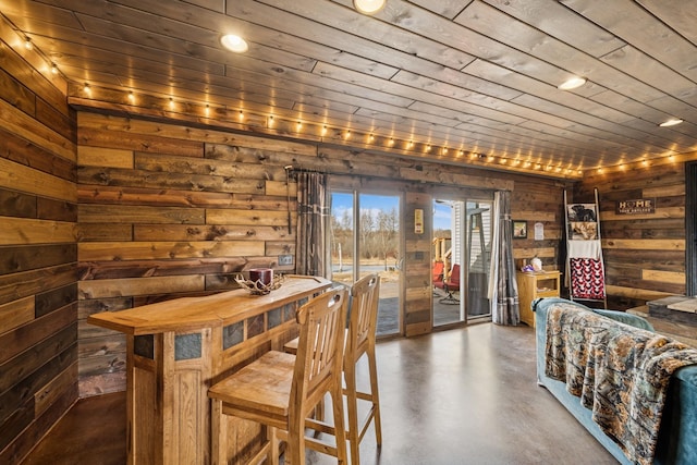 wine area with wood ceiling, wood walls, and finished concrete floors