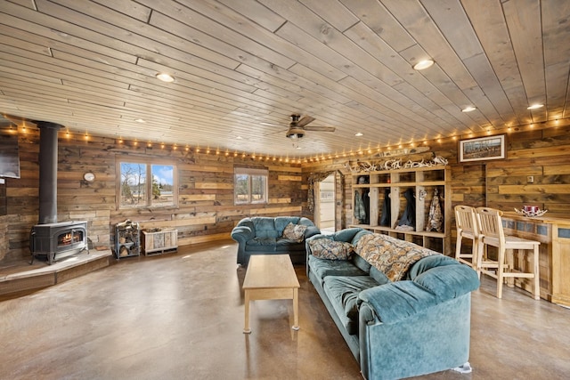 living room with recessed lighting, a ceiling fan, concrete flooring, and a wood stove