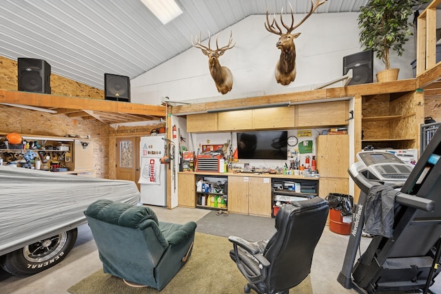 living room with vaulted ceiling, a workshop area, and concrete flooring