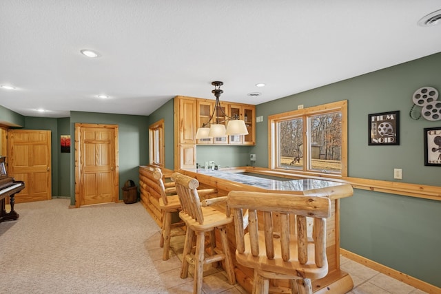 kitchen featuring visible vents, glass insert cabinets, baseboards, decorative light fixtures, and recessed lighting