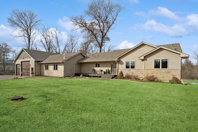 back of house featuring brick siding, a yard, a deck, a garage, and driveway