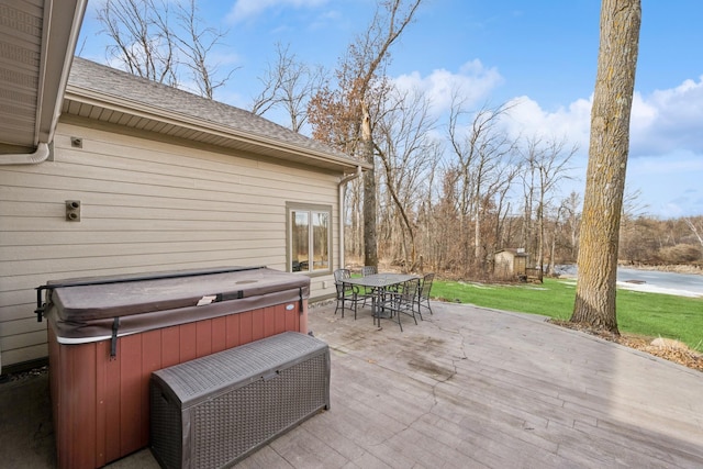 wooden terrace with outdoor dining area, a lawn, and a hot tub