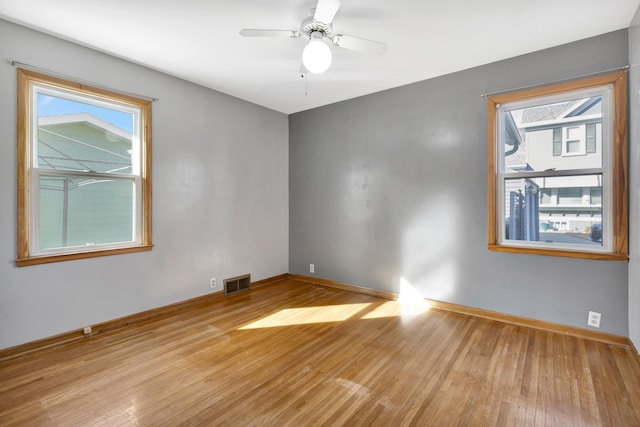 unfurnished room featuring visible vents, a wealth of natural light, and wood finished floors