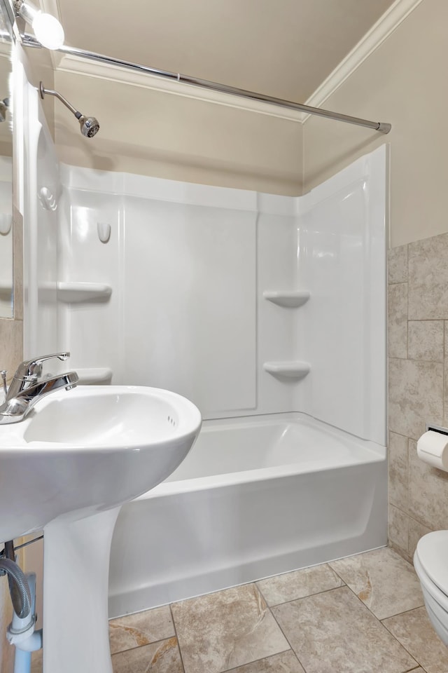 full bath featuring tile walls, shower / bathtub combination, toilet, ornamental molding, and a sink