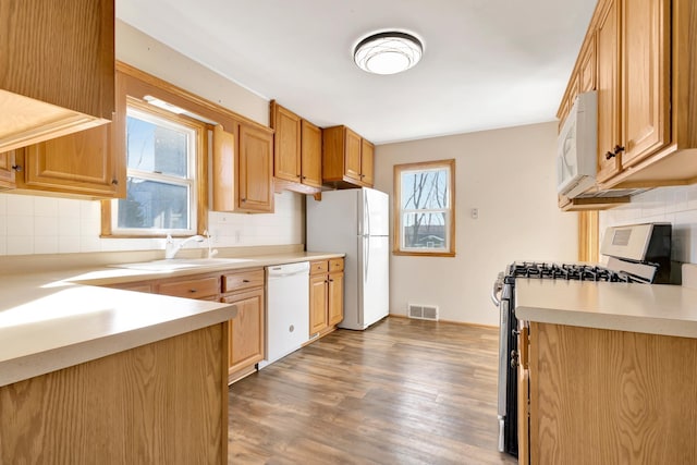 kitchen featuring a healthy amount of sunlight, white appliances, visible vents, and wood finished floors