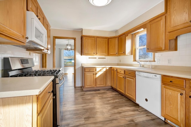 kitchen with white appliances, backsplash, a sink, and light wood-style flooring