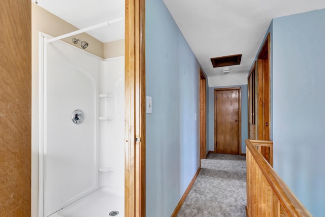 hallway with carpet floors, attic access, baseboards, and an upstairs landing