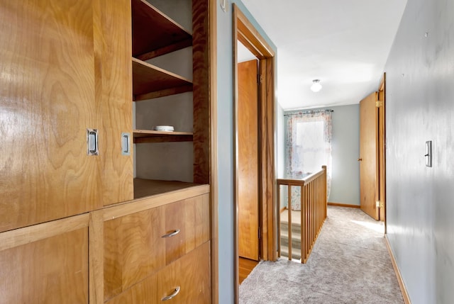 hallway with carpet, an upstairs landing, and baseboards