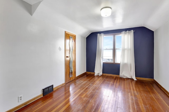 bonus room with hardwood / wood-style flooring, baseboards, visible vents, and vaulted ceiling