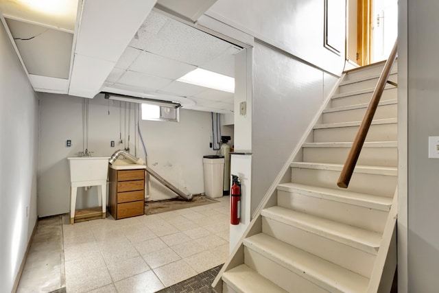 basement with stairs, a paneled ceiling, and tile patterned floors