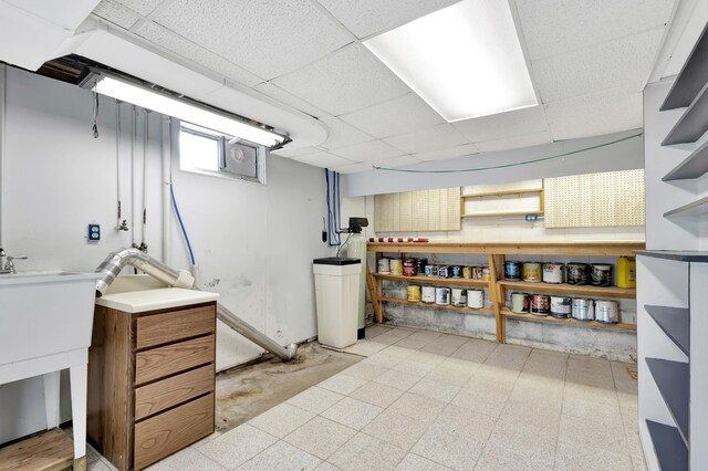 basement featuring a paneled ceiling and light floors