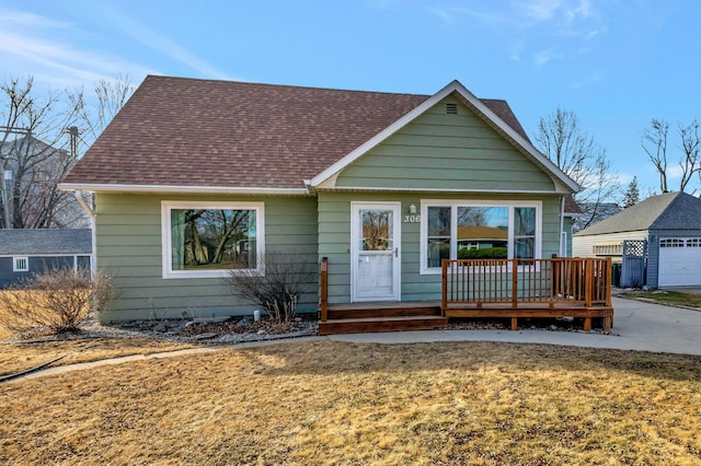 view of front of property with roof with shingles, a front yard, and an outbuilding