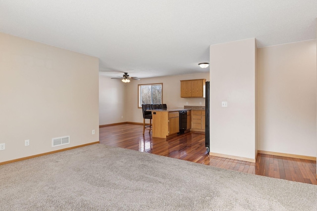 unfurnished living room with visible vents, hardwood / wood-style floors, carpet flooring, baseboards, and ceiling fan