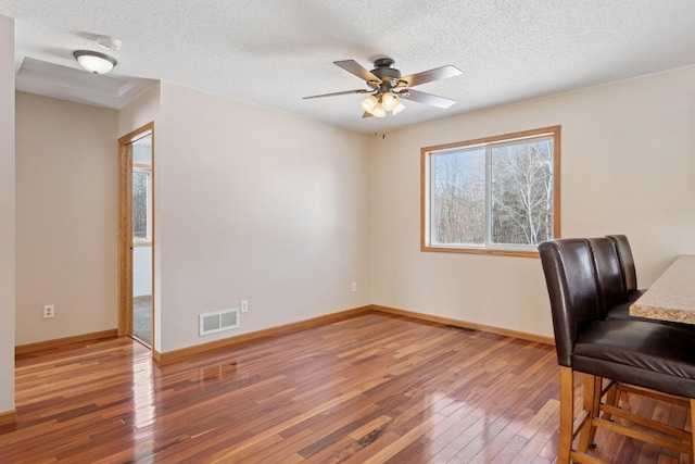 office space with visible vents, a textured ceiling, baseboards, and hardwood / wood-style floors