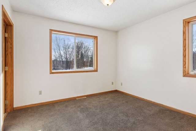 unfurnished room featuring visible vents, carpet, baseboards, and a textured ceiling