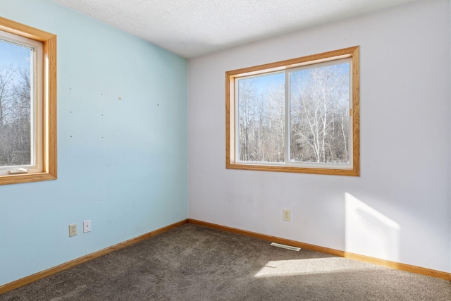 carpeted empty room with visible vents, baseboards, and a textured ceiling