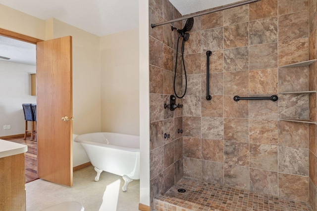 full bathroom with baseboards, a soaking tub, vanity, and a tile shower