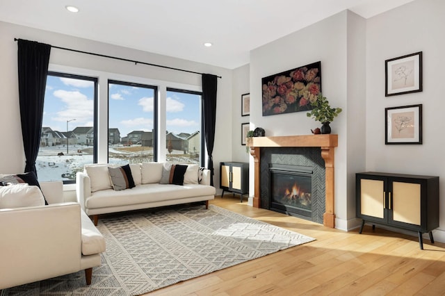 living area featuring wood-type flooring, a tile fireplace, and recessed lighting