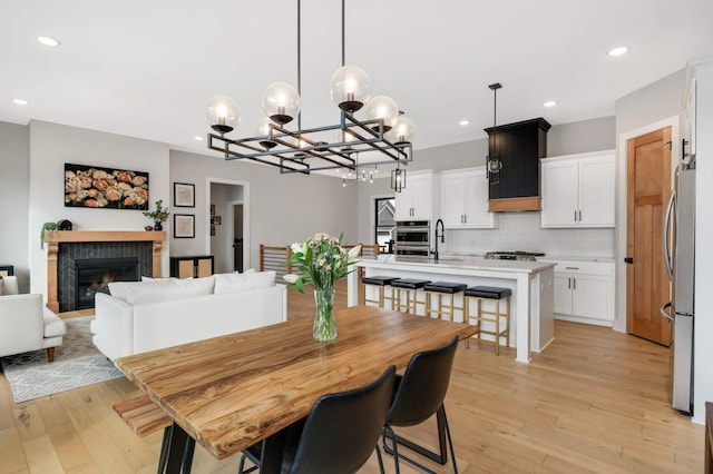 dining area featuring a glass covered fireplace, light wood finished floors, and recessed lighting