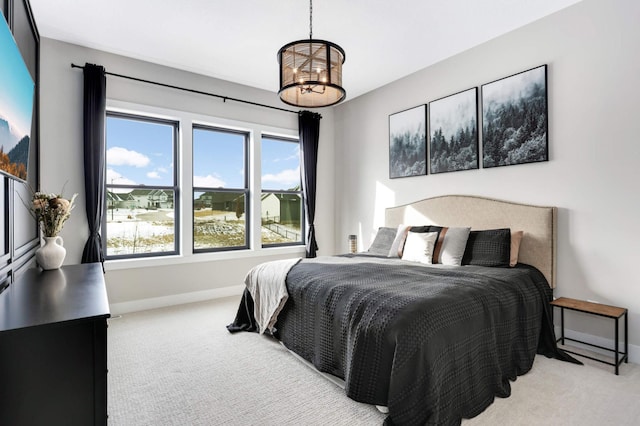 bedroom featuring light carpet, baseboards, and a notable chandelier