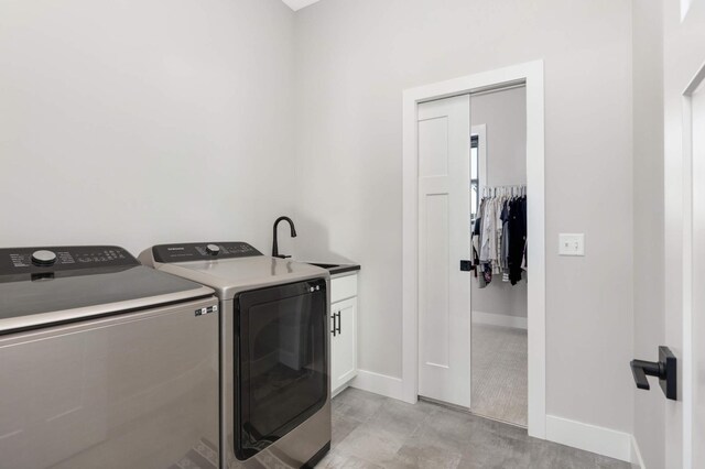 laundry room featuring baseboards, cabinet space, a sink, and washing machine and clothes dryer