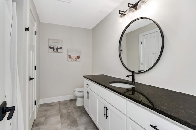 bathroom featuring baseboards, vanity, and toilet