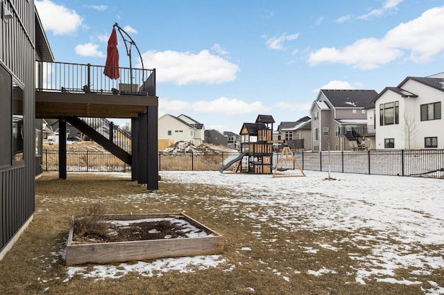 yard covered in snow featuring a vegetable garden, a fenced backyard, a residential view, stairway, and a playground