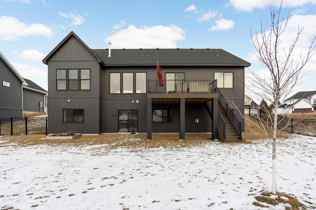 snow covered rear of property with fence, a wooden deck, and stairs