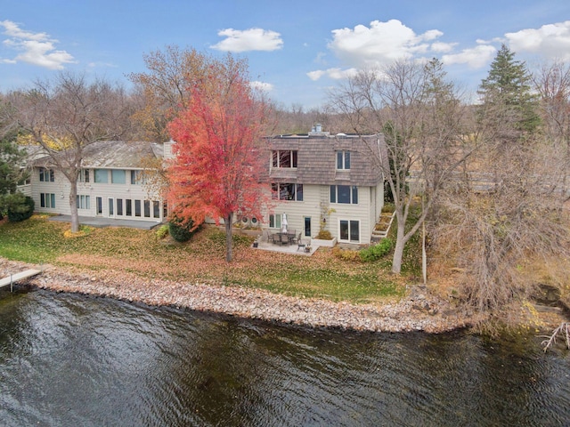 back of house with a patio area, a water view, and mansard roof