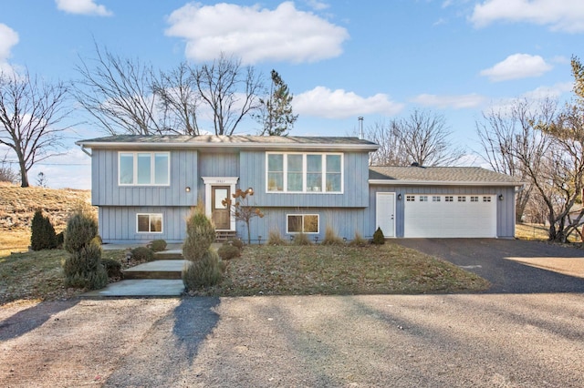 raised ranch featuring an attached garage and driveway