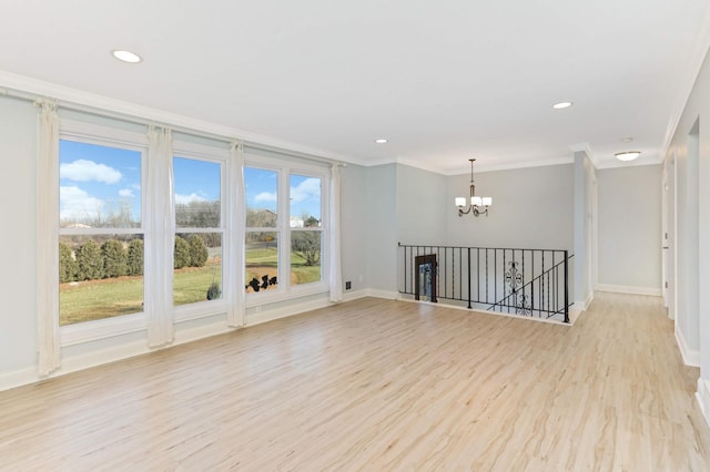 spare room featuring baseboards, ornamental molding, light wood-style flooring, and a chandelier
