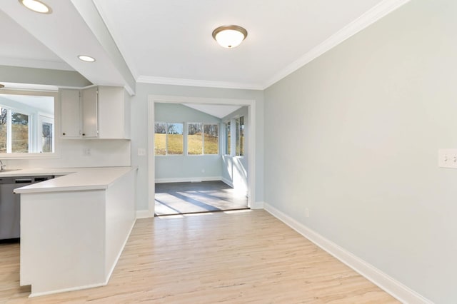 kitchen with light countertops, crown molding, a peninsula, and light wood finished floors