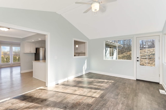 unfurnished living room with dark wood-style flooring, ceiling fan, baseboards, and lofted ceiling