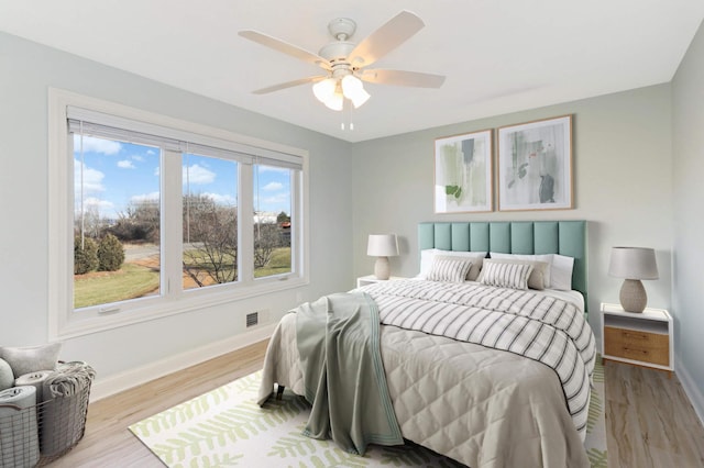 bedroom with ceiling fan, baseboards, visible vents, and wood finished floors
