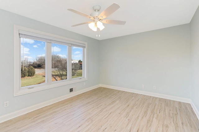 spare room featuring baseboards, visible vents, ceiling fan, and light wood-style floors