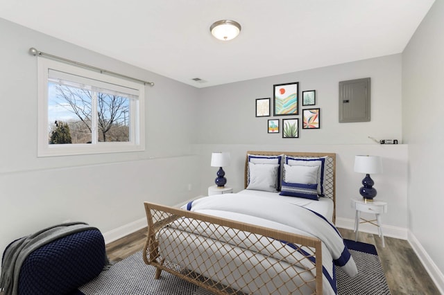 bedroom with baseboards, wood finished floors, and electric panel