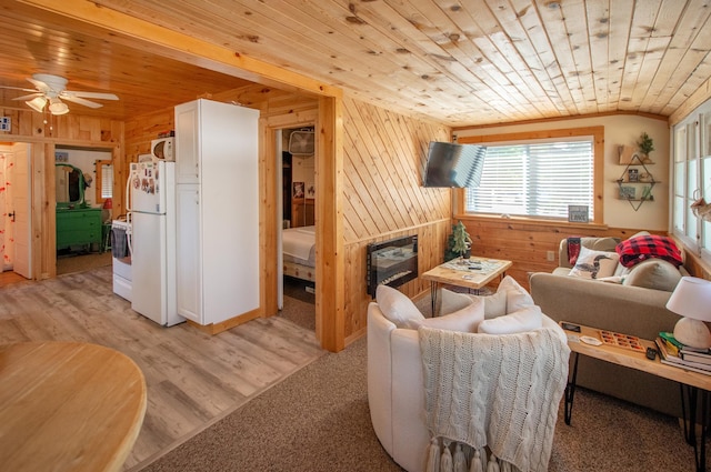 living area featuring a glass covered fireplace, light wood-style floors, wood ceiling, and wood walls