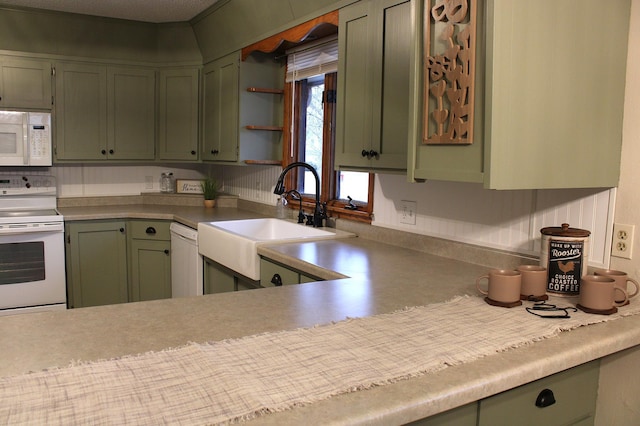 kitchen with open shelves, light countertops, green cabinets, a sink, and white appliances