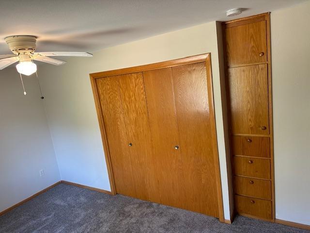 unfurnished bedroom featuring carpet floors, a closet, ceiling fan, and baseboards