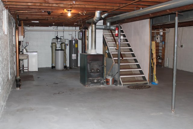 unfinished below grade area with stairs, washer / clothes dryer, electric water heater, and concrete block wall