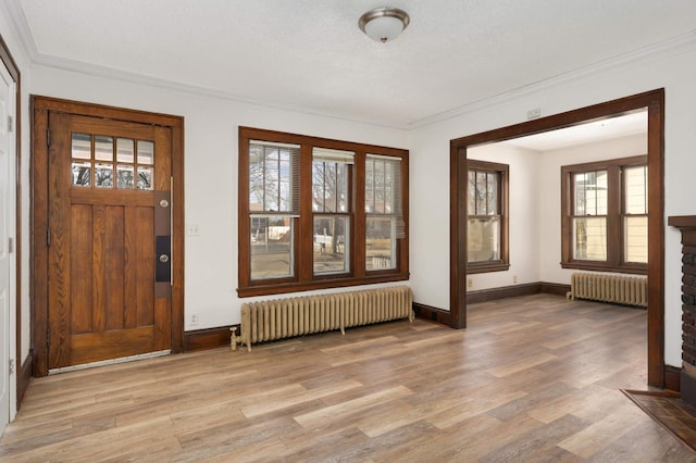 entrance foyer featuring light wood-style flooring, radiator, and ornamental molding