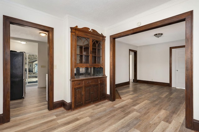 interior space with light wood finished floors, crown molding, freestanding refrigerator, and baseboards