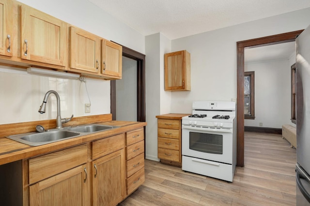 kitchen featuring light wood finished floors, butcher block counters, white range with gas stovetop, a textured ceiling, and a sink