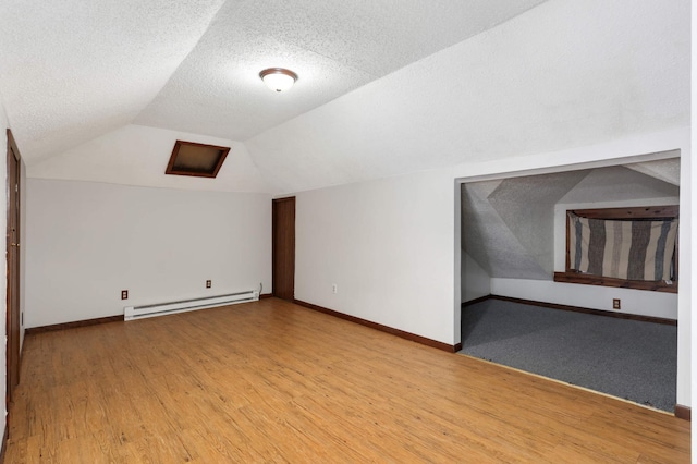 additional living space with light wood-style floors, lofted ceiling, baseboard heating, and a textured ceiling