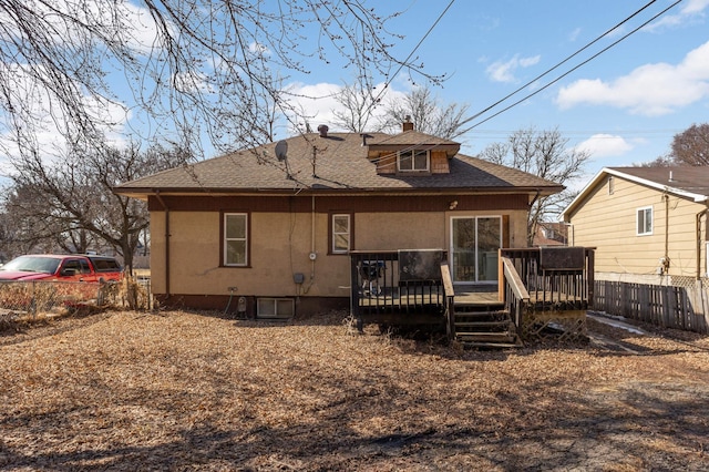 back of property with a shingled roof, fence, a wooden deck, stucco siding, and a chimney