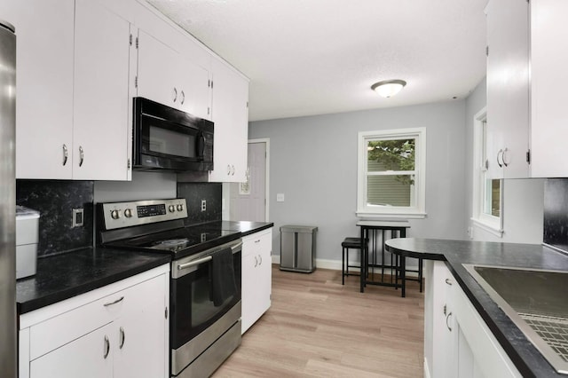 6719 Ewing Ave N, Brooklyn Center, MN 55429 - kitchen featuring black microwave, stainless steel electric range, backsplash, dark countertops, and white cabinets